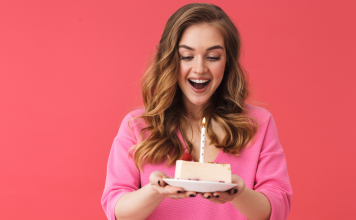 woman holding slice of birthday cake with a candle in it