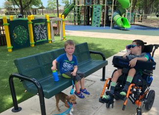 child in wheelchair and preschooler at accessible playground
