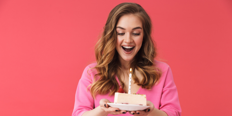 woman holding birthday cake slice with candle
