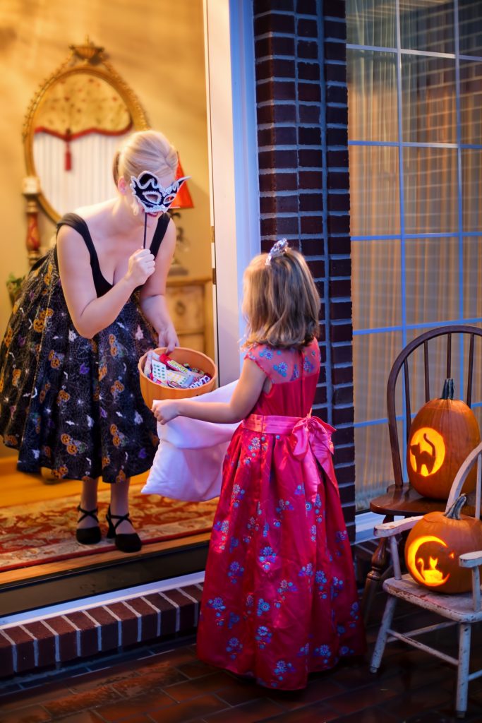 woman opens the door for trick or treater