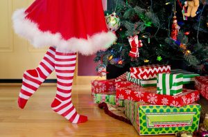 girl in striped tights and santa skirt tip toes by tree