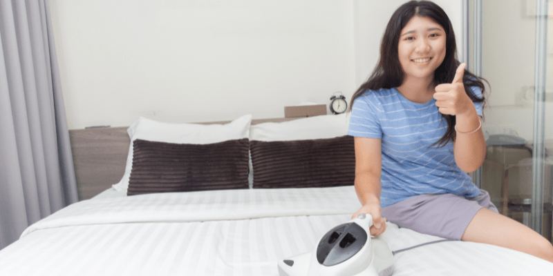 Woman finishes one of the yearly tasks-cleaning the mattress- and gives a thumbs up while sitting on the bed