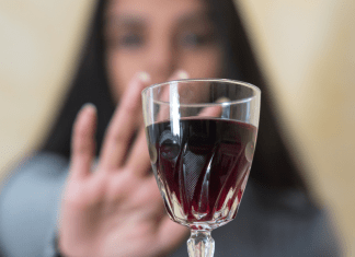 woman pushes away glass of wine