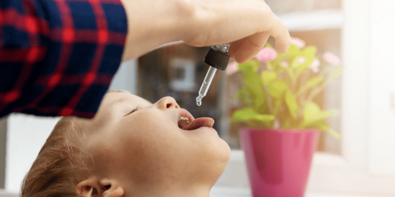 child takes vitamin from a dropper