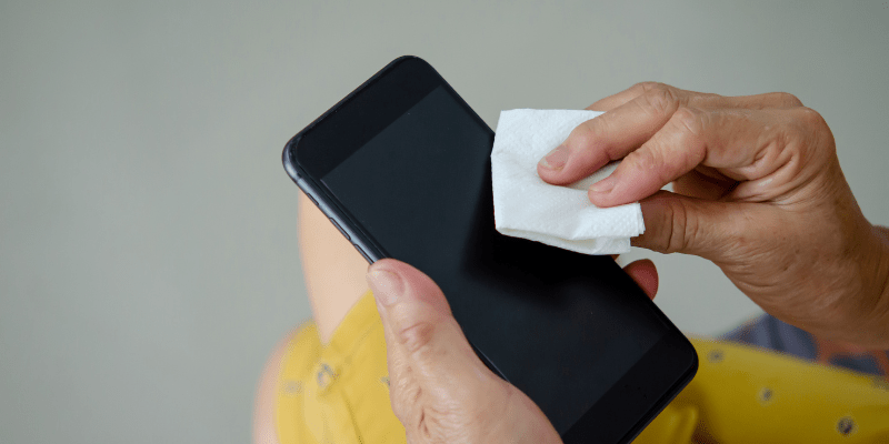 person wipes off phone with cleaning cloth