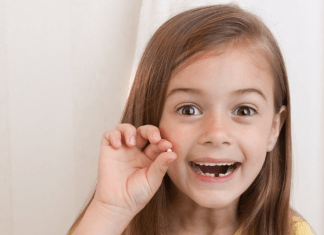 girl holds up lost tooth