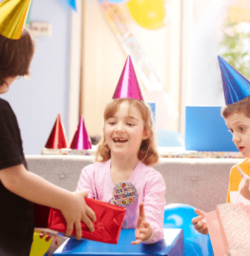 children giving girl a birthday gift