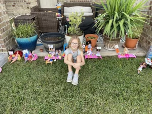 girl in front of a line of Barbie dolls