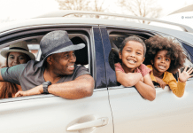 family of four with heads out the car windows, smiling