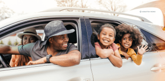 family of four with heads out the car windows, smiling