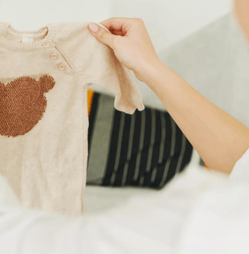 woman holding up baby onesie