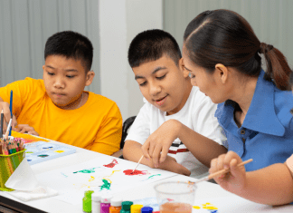 children sit at table painting