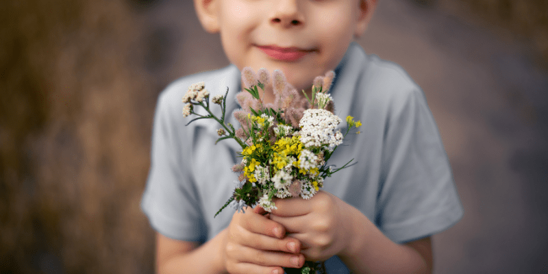 young boy holds a bunch of wildflowers
