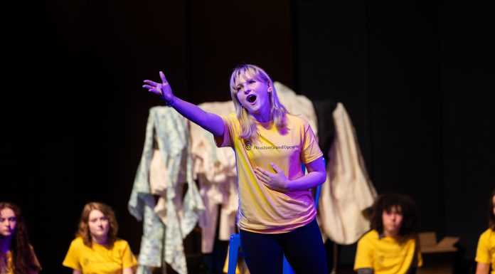 A girl singing with arm outstretched on stage