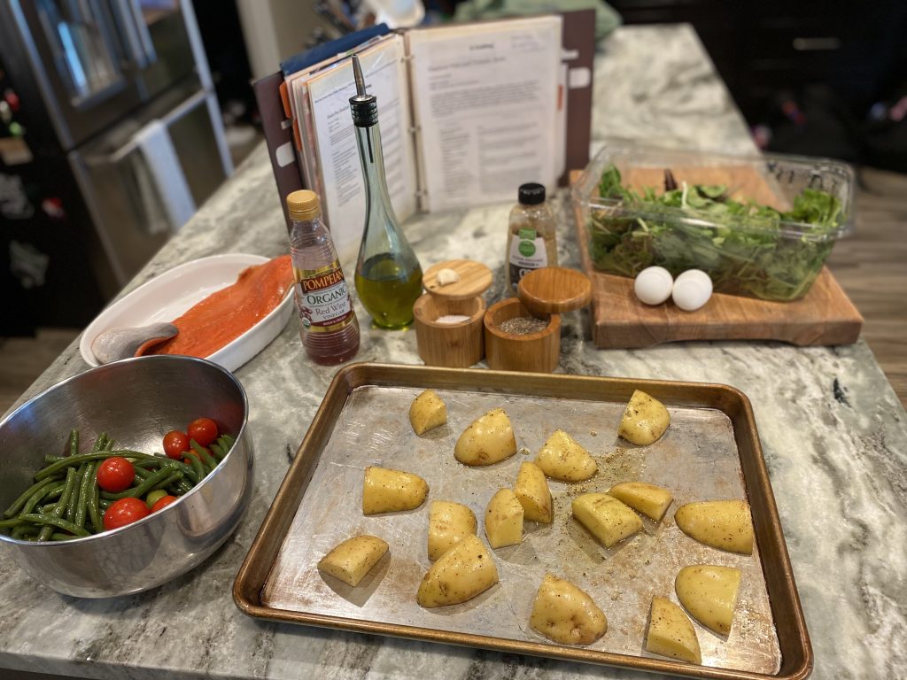 sheet pan of potatoes beside a bowl of green beans and tomatoes