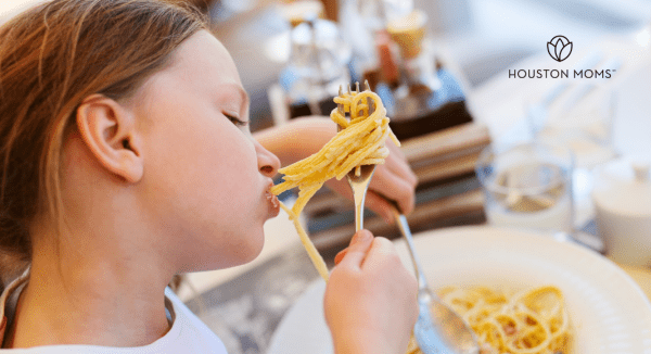 young girl eating spaghetti noodles