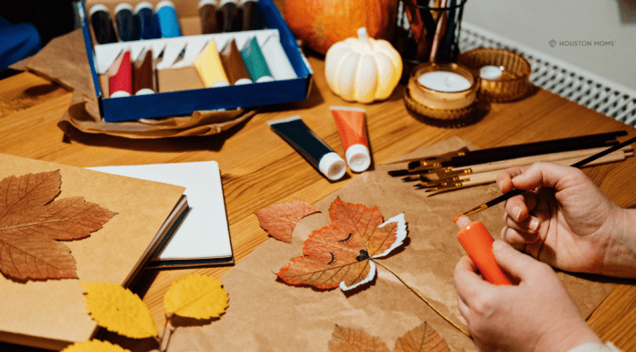 Fall Crafts for the Entire Family a table covered in leaves, paint, and a hand holding a paintbrush completing fall crafts