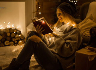 woman reading in front of lights and fire