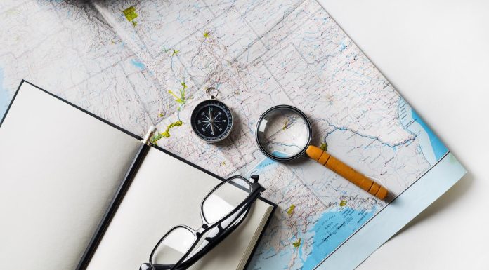 image of an open blank journal, a compass and magnifying glass on a map