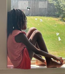 child sitting on windowsill looking into yard