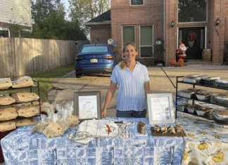 woman stands behind table filled with sourdough bread