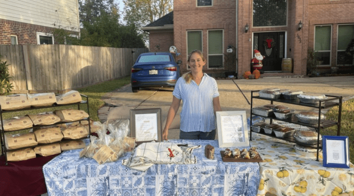woman stands behind table filled with sourdough bread