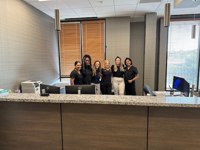 Staff smile for a photo behind a desk.