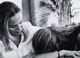 mother with arm around daughter whose head is on the table