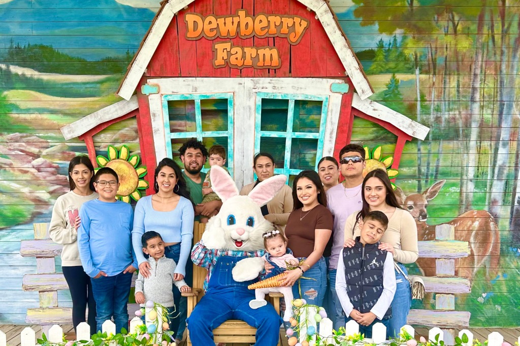 a family poses with the Easter bunny in front of a red barn that says Dewberry Farm