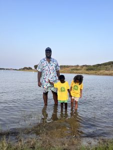 family standing on edge of lake