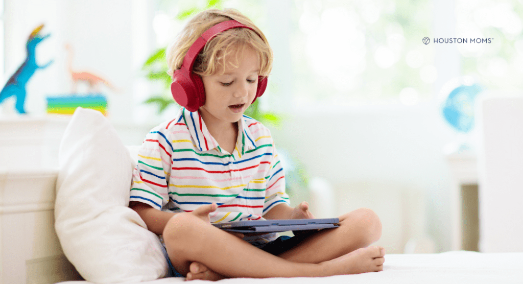 boy with headphones sits with tablet playing learning apps