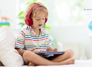 boy with headphones sits with tablet playing learning apps