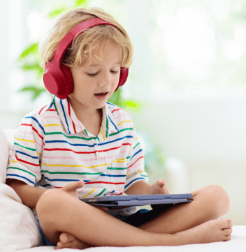 Best Apps for Kids to Encourage Learning boy with headphones sits with tablet playing learning apps