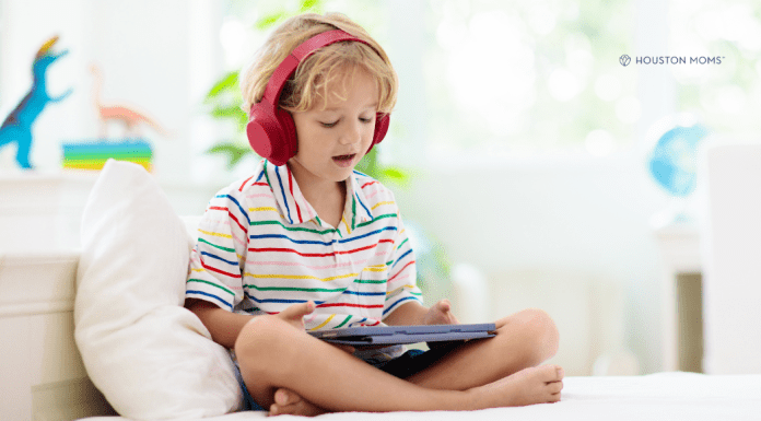 Best Apps for Kids to Encourage Learning boy with headphones sits with tablet playing learning apps