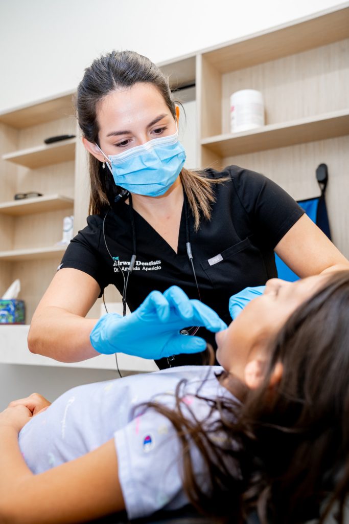 A dentist examines a girl's mouth