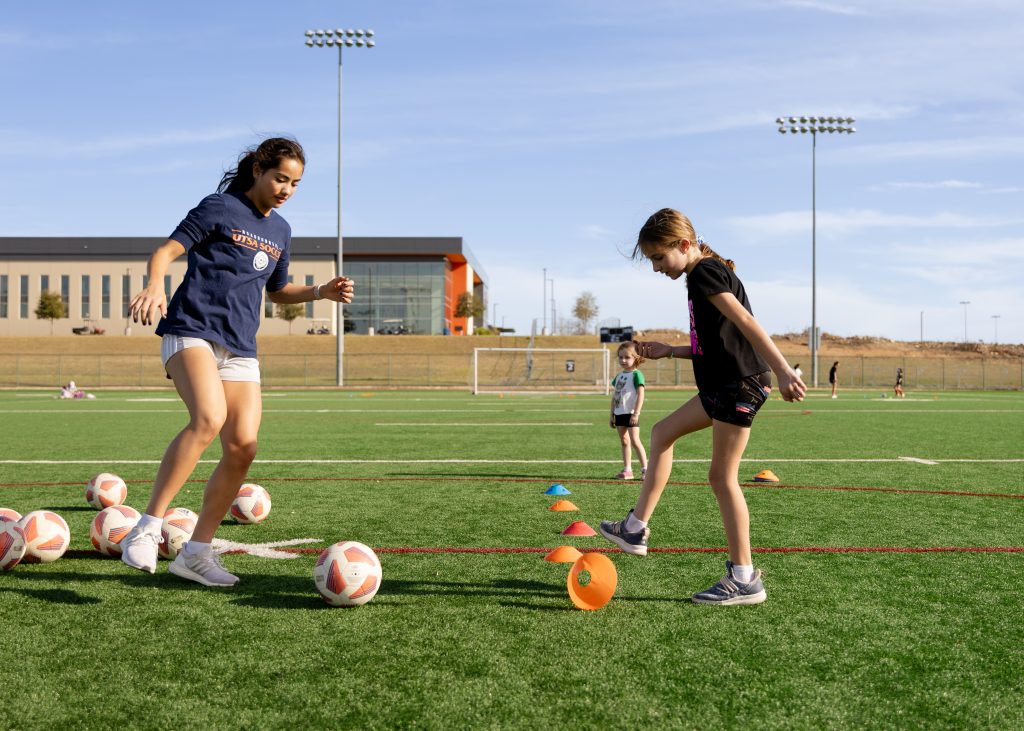 Kids kick soccer balls on a field.