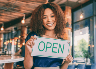 woman owning small business holds "Open" sign