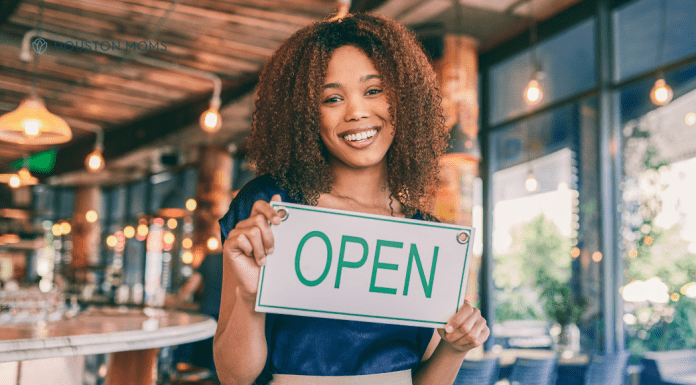 woman owning small business holds "Open" sign