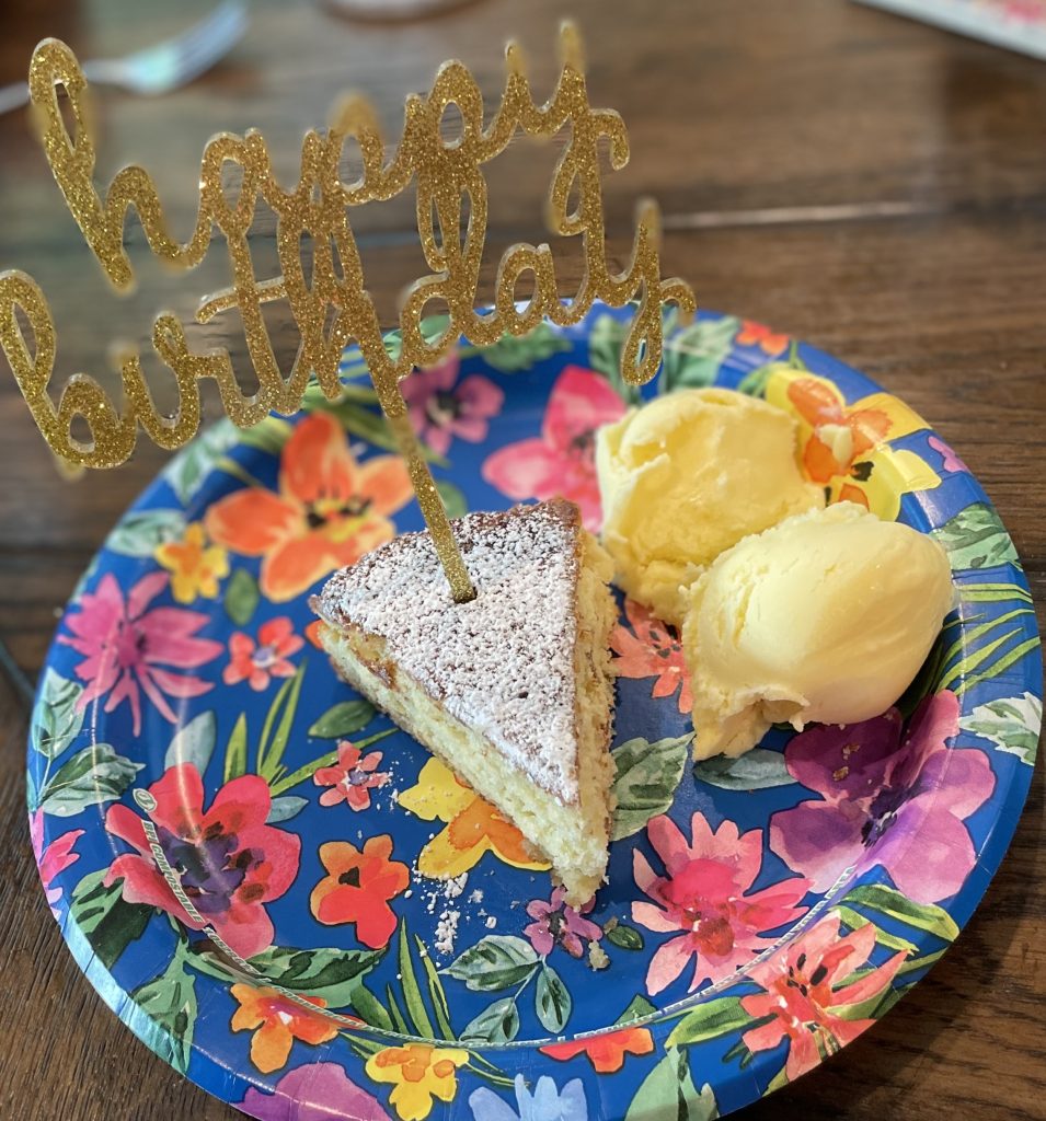 slice of birthday cake on a paper plate with a side of homemade ice cream