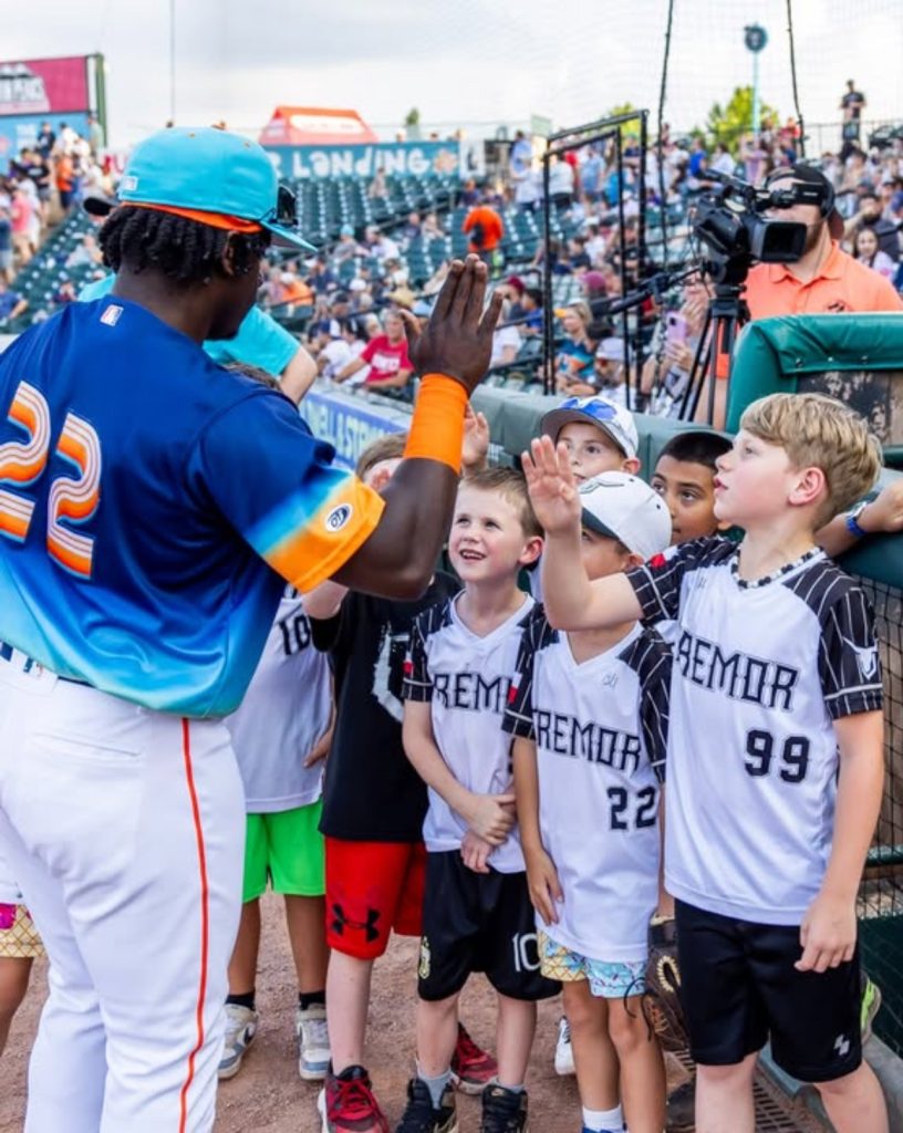 Kids high five a baseball player at a space cowboys game.