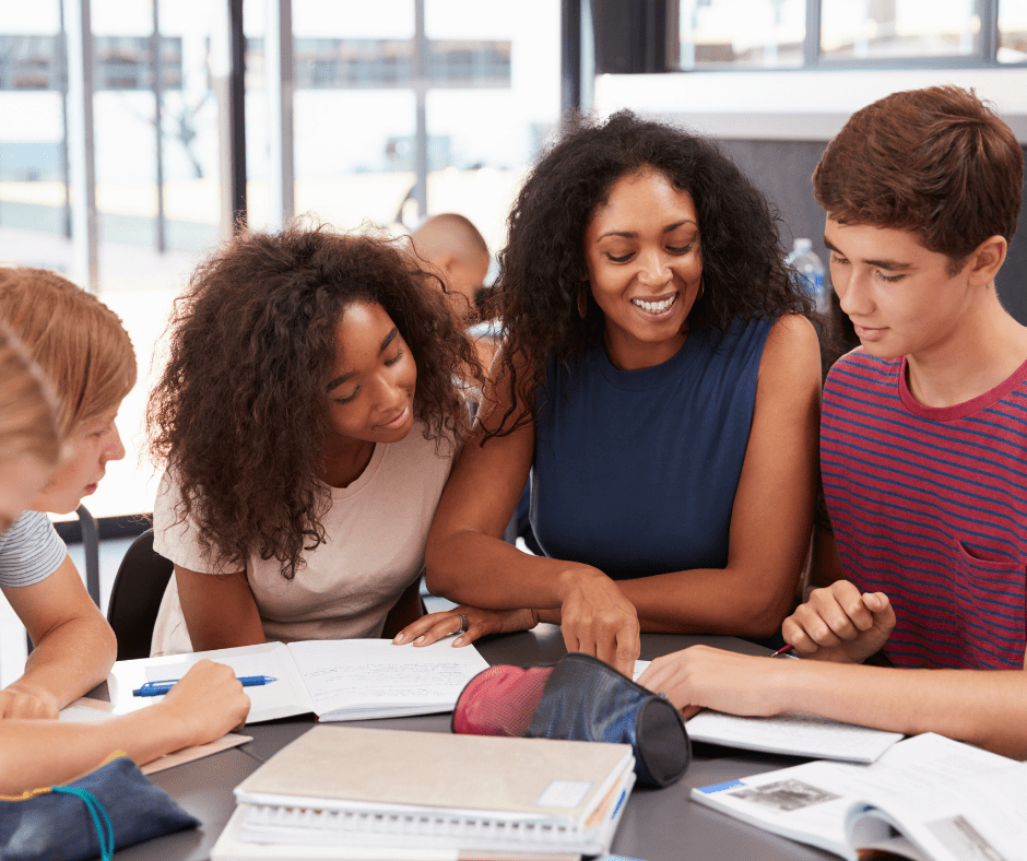 students gather around a table, studying
