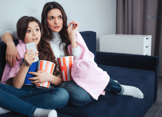 mother and daughter sitting on couch with popcorn