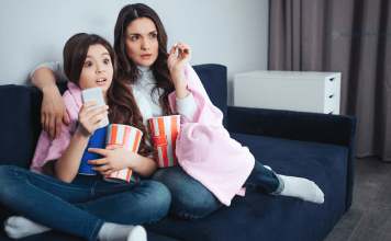 Watching Late 90s/Early 2000s RomComs Through a Modern Lens mother and daughter sitting on couch with popcorn