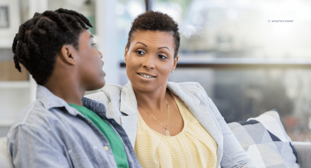 mother and college aged son sit and talk on couch