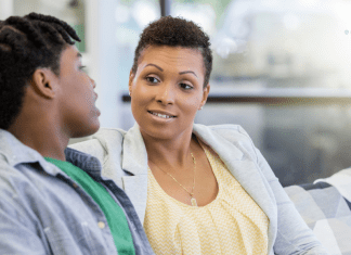 mother and college aged son sit and talk on couch