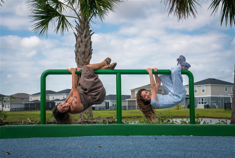 Young woman and girl hang on a piece of playground equipment