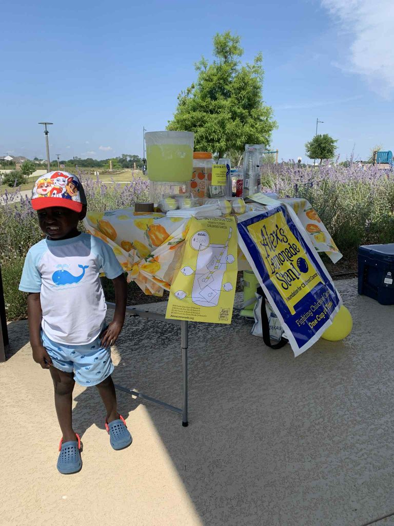 child standing in front of lemonade stand