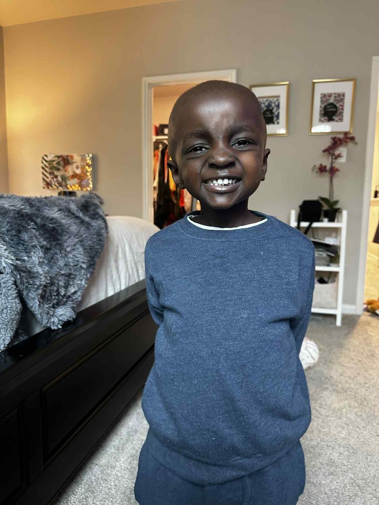 smiling child stands in bedroom