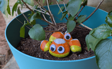 rocks painted like candy corn with googly eyes sit in pot