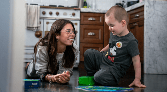 Childcare Stress? Consider Hosting an Au Pair Young woman sits on floor with toddler